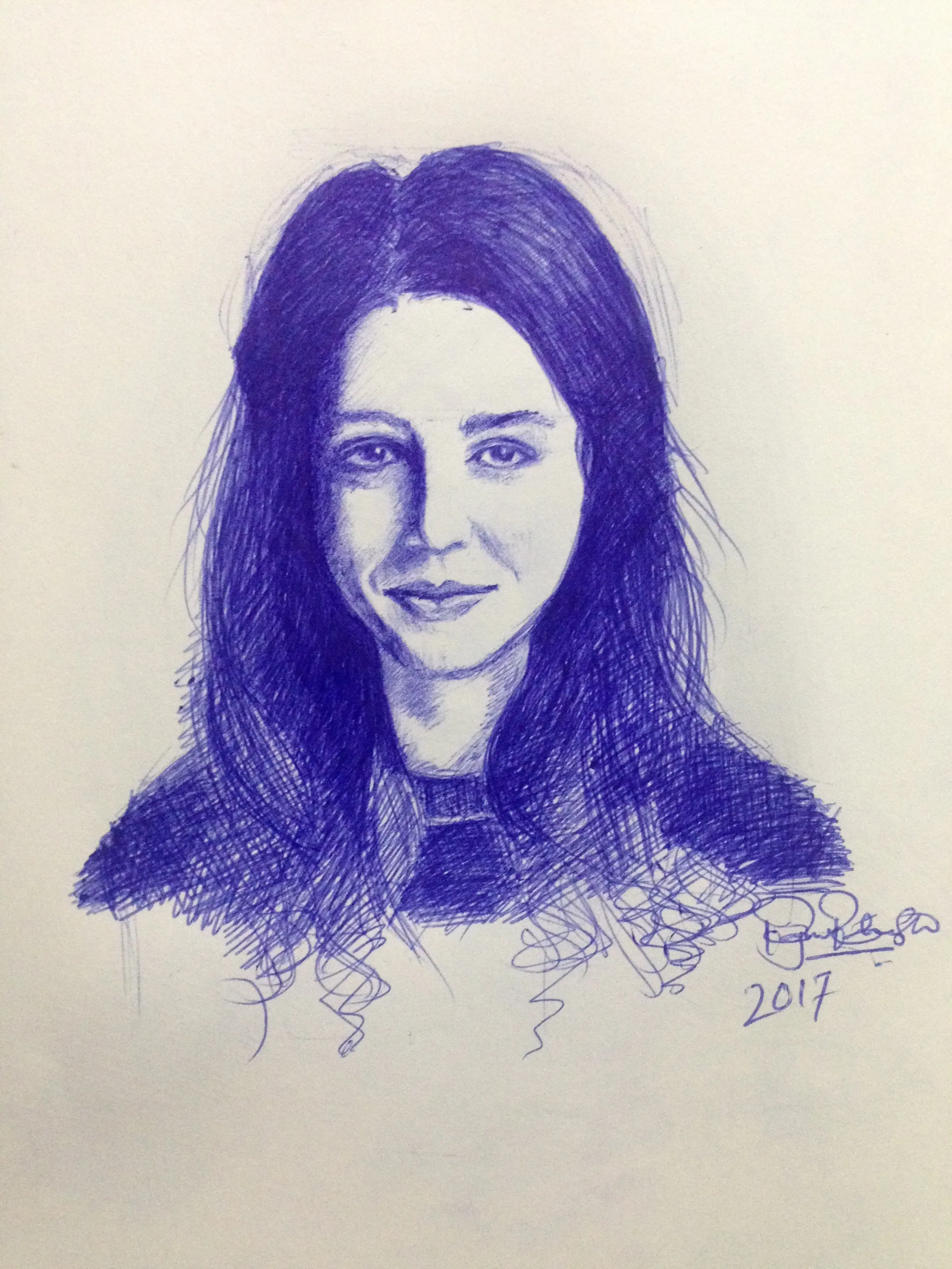 Blue ballpen portrait of a woman with long dark centre-parted hair on cream paper, with a scribbled signature and the year 2017 written below.
